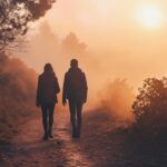 Couple walking on a foggy trail at sunrise with trees and warm sunlight