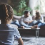 Young girl looking at parents sitting on couch in a cozy living room setting