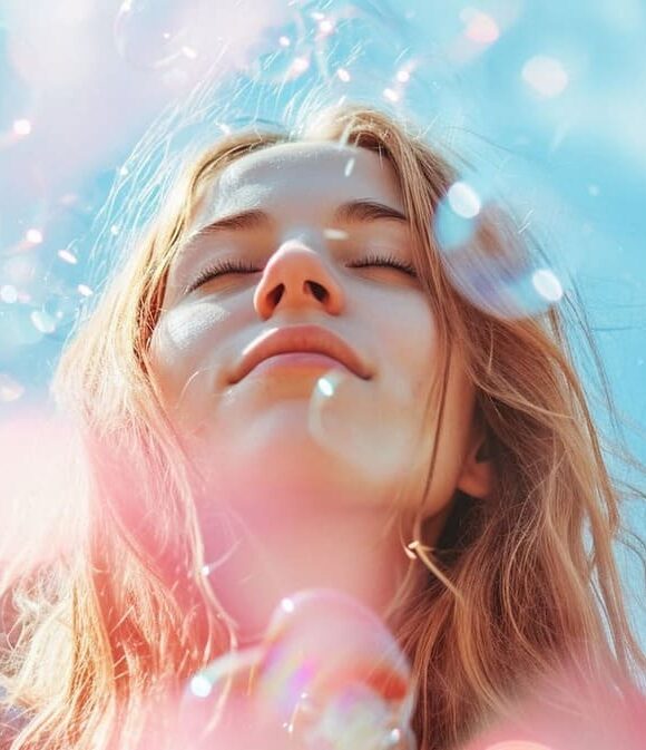 Young woman enjoying sunlight amidst soap bubbles against a blue sky background.