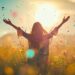 Woman enjoying freedom in a meadow with colorful confetti floating in the air at sunset