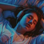 Young woman sleeping with headphones in a bed under blue lighting