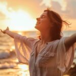 Happy woman embracing freedom with open arms on beach at sunset