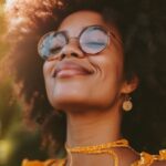 Happy African American woman with curly hair wearing glasses and smiling in sunlight